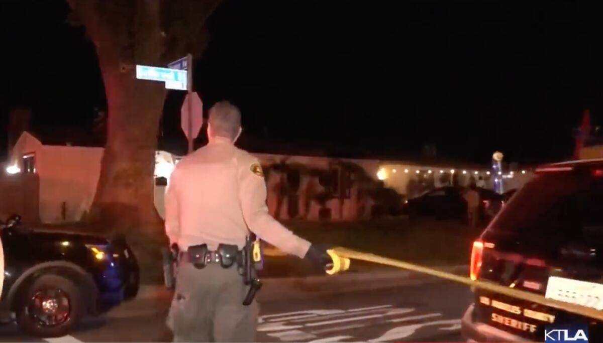 A deputy rolls out crime scene tape next to sheriff SUVs parked outside a home