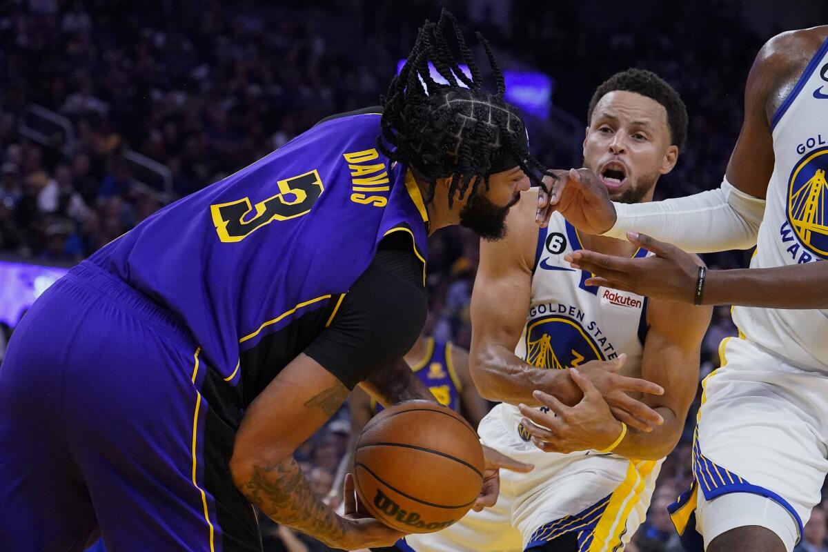 Lakers forward Anthony Davis and Golden State Warriors guard Stephen Curry compete for possession of the ball.