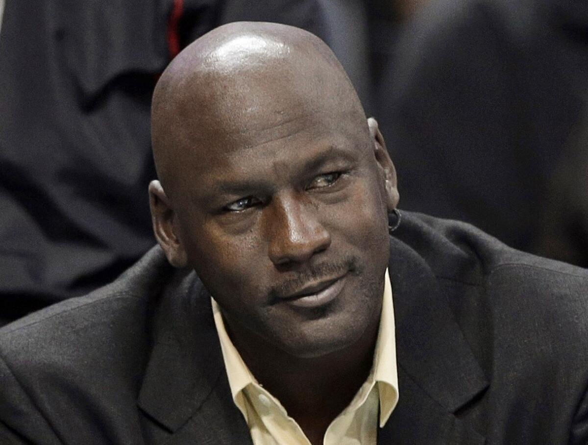 Michael Jordan looks on from the sideline at a Charlotte Hornets game