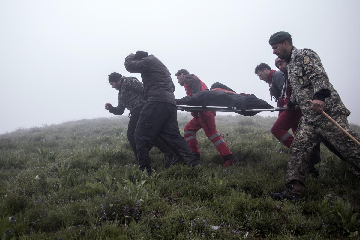 Rescue team members carry the body of a victim on a stretcher amid fog after a helicopter crashed.