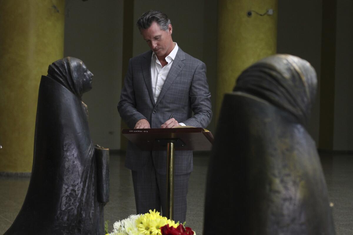 California Gov. Gavin Newsom writes a note in a book at the tomb of Saint Oscar Romero at Metropolitan Cathedral in San Salvador, El Salvador, on Sunday.