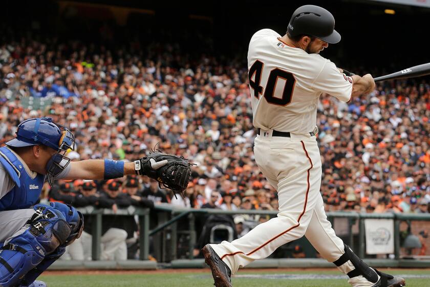 Madison Bumgarner hits a solo home run in front of Dodgers catcher A.J. Ellis on April 9.