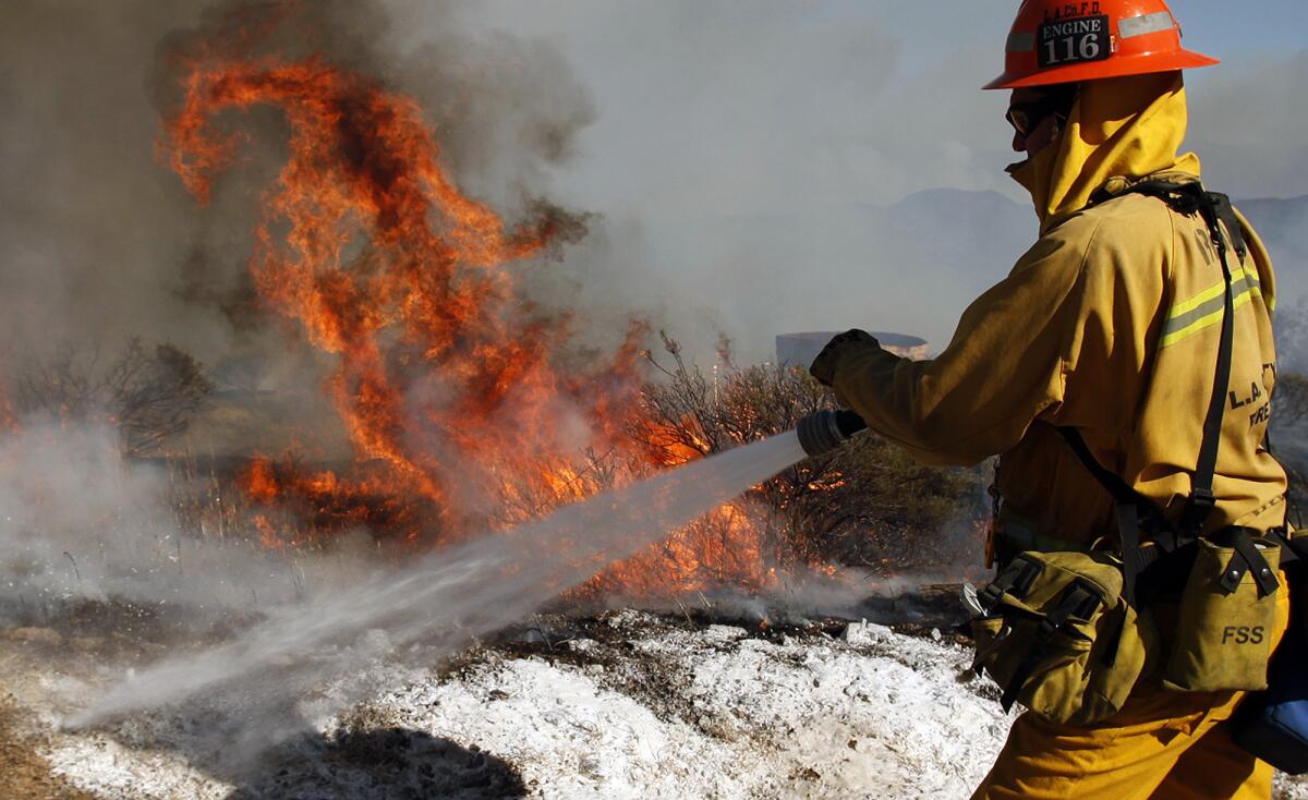 L.A. County firefighters battle hot spots from the Springs fire in the mountains above Malibu.