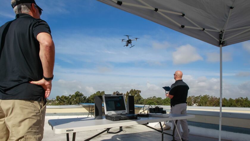 Chula Vista officers on the rooftop of the police station watch a drone come in for landing
