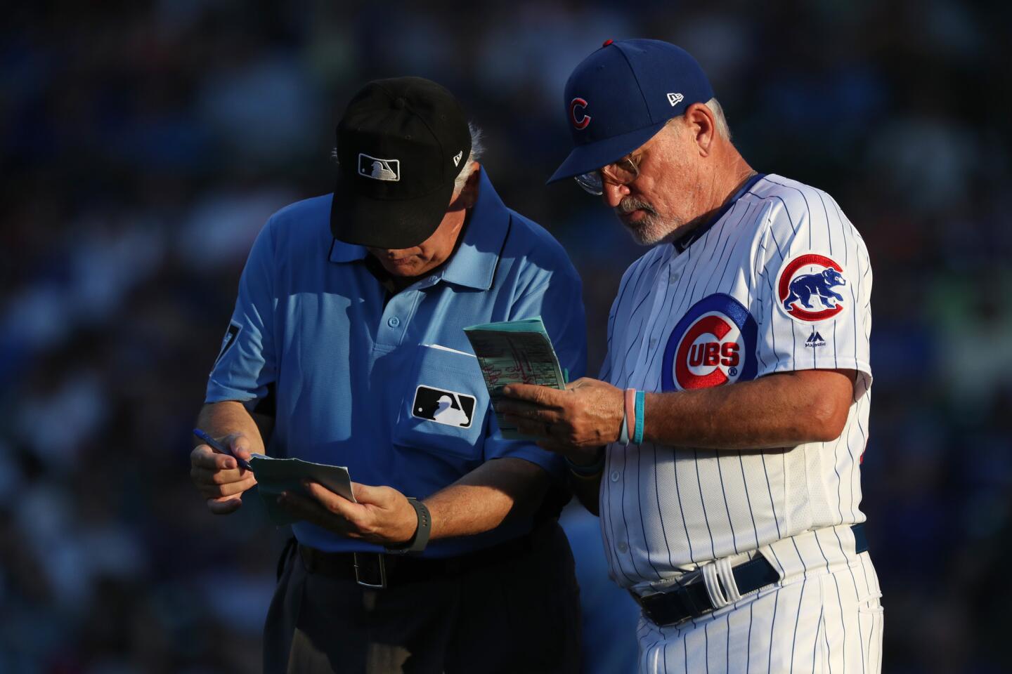Cubs manager Joe Maddon (70) and third base umpire Larry Vanover go over lineup changes in the ninth inning against the Twins at Wrigley Field Friday, June 29, 2018.