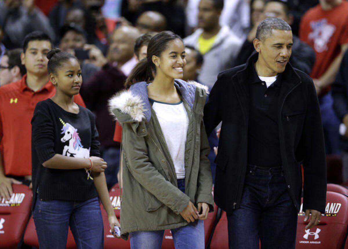 President Obama walks to his seat with daughters Sasha, left, who is clad in the much-coveted Asos sweater, and Malia before a basketball game between Maryland and Oregon State in College Park, Md.