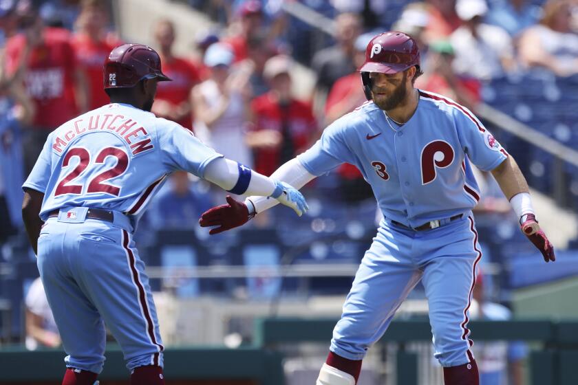 Philadelphia Phillies' Bryce Harper (3) is congratulated by Andrew McCutchen (22) after Harper hit a home run against the Los Angelas Dodgers during the first inning of a baseball game Thursday, Aug. 12, 2021, in Philadelphia. (AP Photo/Rich Schultz)