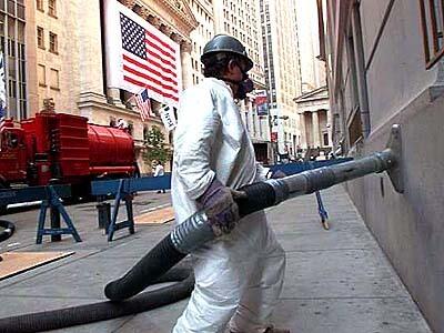 A worker vacuums dust from a Wall Street building
