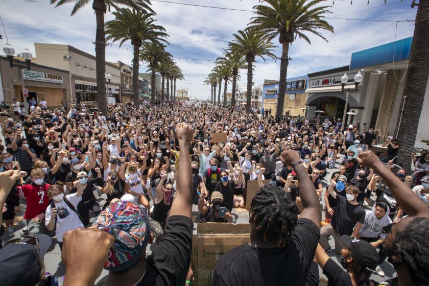HERMOSA BEACH, CA - JUNE 02: Several hundred Black Lives Matter protesters take a knee and hold their fists in the air during a moment of silence to honor George Floyd during a peaceful protest march from Manhattan Beach to Hermosa Beach and return at the Hermosa Beach Pier Plaza Tuesday, June 2, 2020. (Allen J. Schaben / Los Angeles Times)
