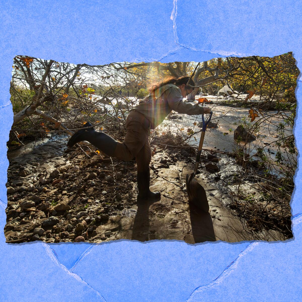 A person in mud boots leans over a shovel next to a running stream. 