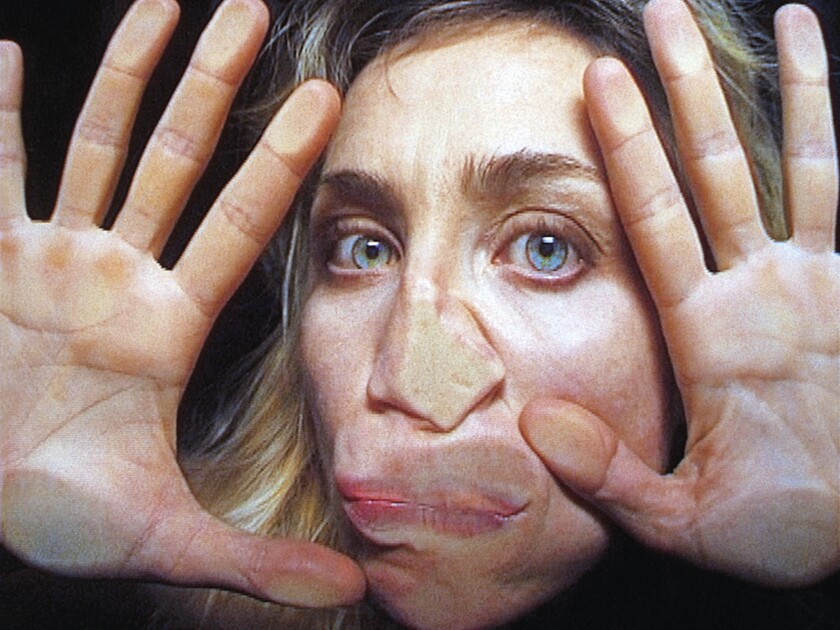 Una imagen del video de Pipilotti Rist de 2000 "Abre mi claro": El rostro y las manos de una mujer miran hacia la cámara, presionadas contra el vidrio.