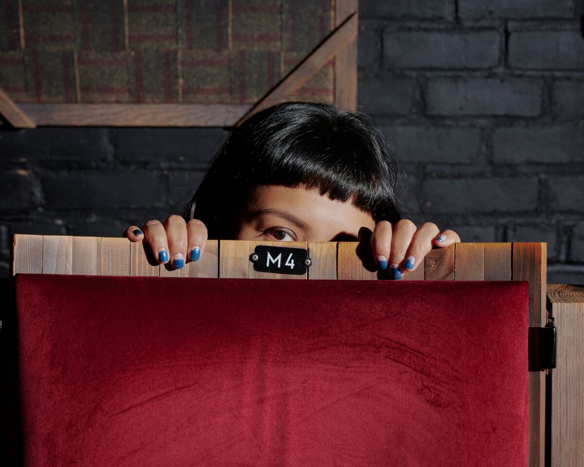 Martika Ramirez Escobar peeks above a theater seat.