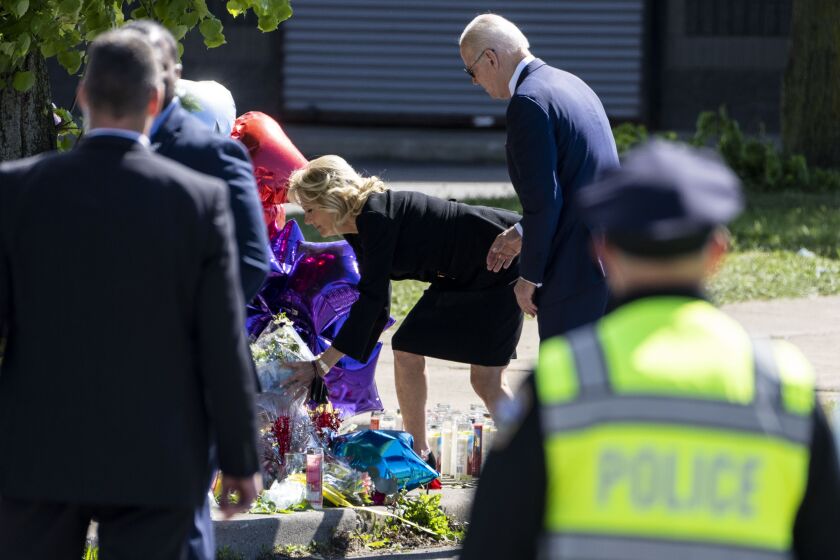 BUFFALO, NY - MAY 17: President Joe Biden stands back as First Lady Dr. Jill Biden places flowers at a memorial just across the street of the Tops Friendly Market at Jefferson Avenue and Riley Street on Tuesday, May 17, 2022 in Buffalo, NY. The Supermarket was the site of a fatal shooting of 10 people at a grocery store in a historically Black neighborhood of Buffalo by a young white gunman is being investigated as a hate crime and an act of "racially motivated violent extremism," according to federal officials. (Kent Nishimura / Los Angeles Times)