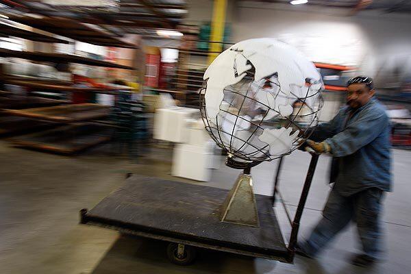 Jorge Salazar wheels a globe to be placed on the Cunard Line float under construction at Fiesta Parade Floats in Irwindale. The firm has built 17 consecutive Sweepstakes Trophy winners in the Rose Parade.