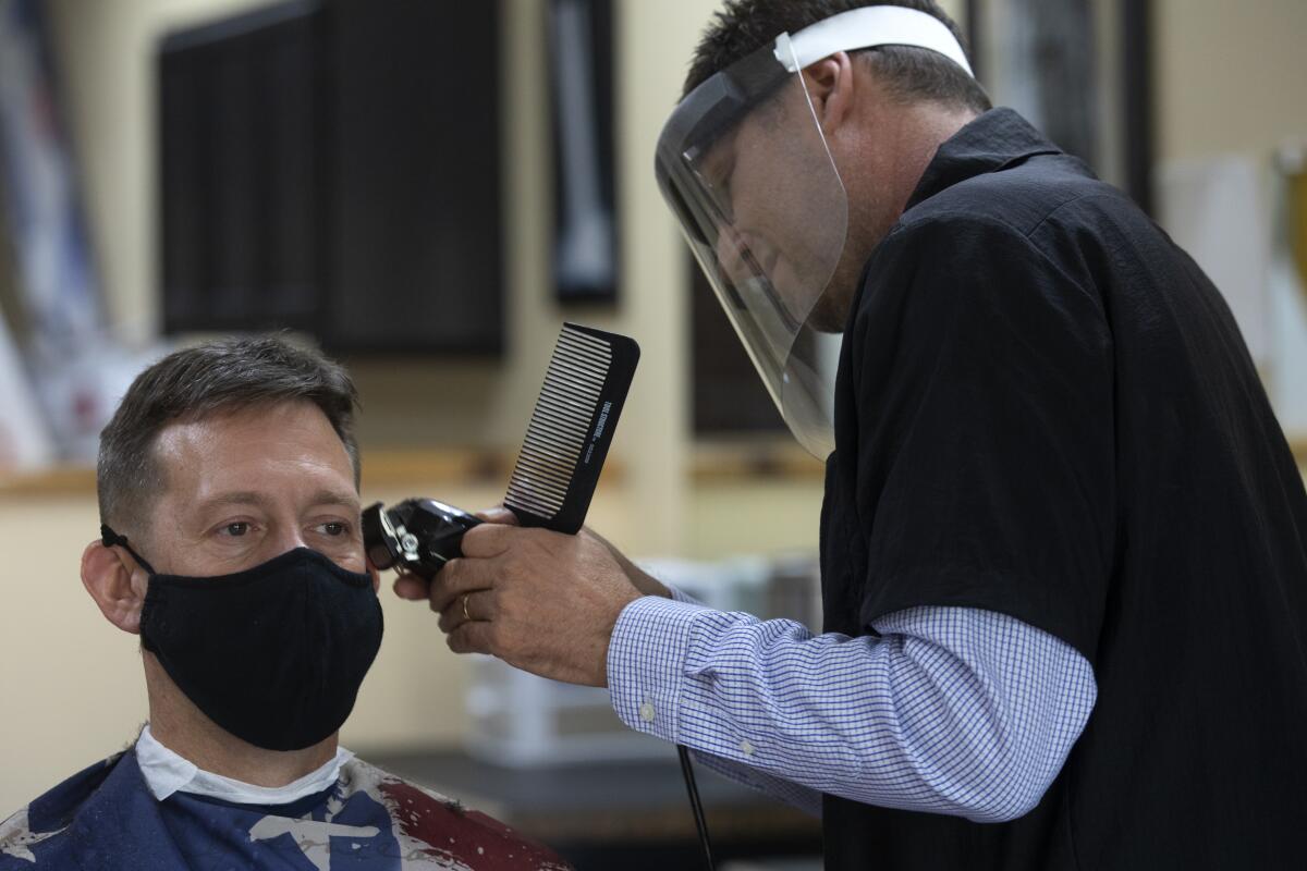 Gene Kelley, right, co-owner of Skyline Barber Shop, cuts Dan Collins' hair on Tuesday in Temecula.