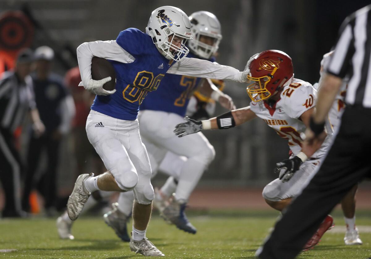 Fountain Valley wide receiver Blake Anderson stiff-arms Woodbridge's Owen Lucas in the first half of a nonleague game on Thursday at Huntington Beach High.