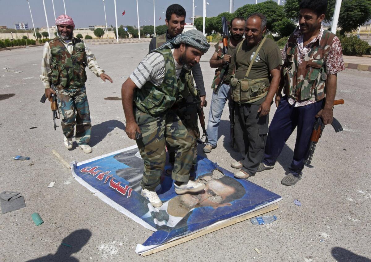 A Free Syrian Army fighter steps on a portrait of Syrian President Bashar Assad.