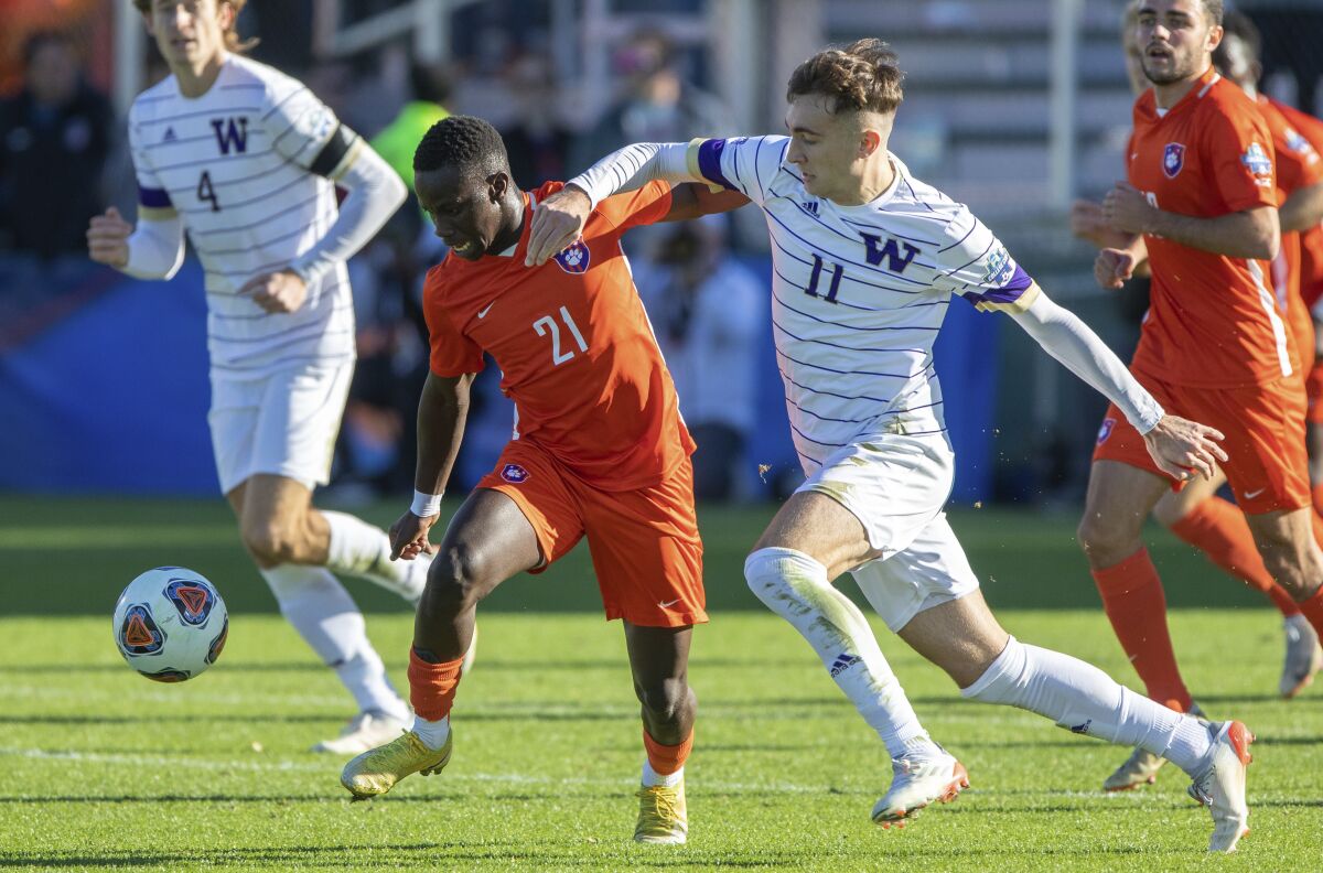 Clemson's Ousmane Sylla (21) and Washington's Nick Scardina (11) battle for a ball during the first half of the NCAA college soccer tournament championship in Cary, N.C., Sunday, Dec. 12, 2021. (AP Photo/Ben McKeown)