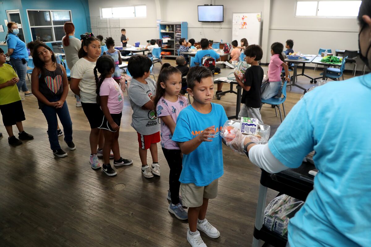 Children line up as Reema Mohammad hands out nutritional meal packages at the Boys & Girls Club on July 22.
