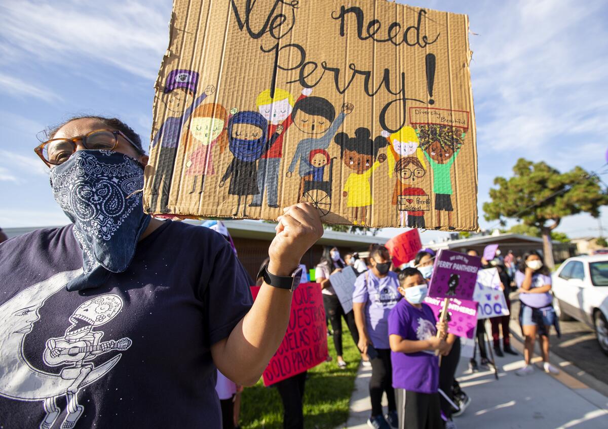 Diane Parras, an alumni of Perry Elementary School in Huntington Beach, holds a sign.