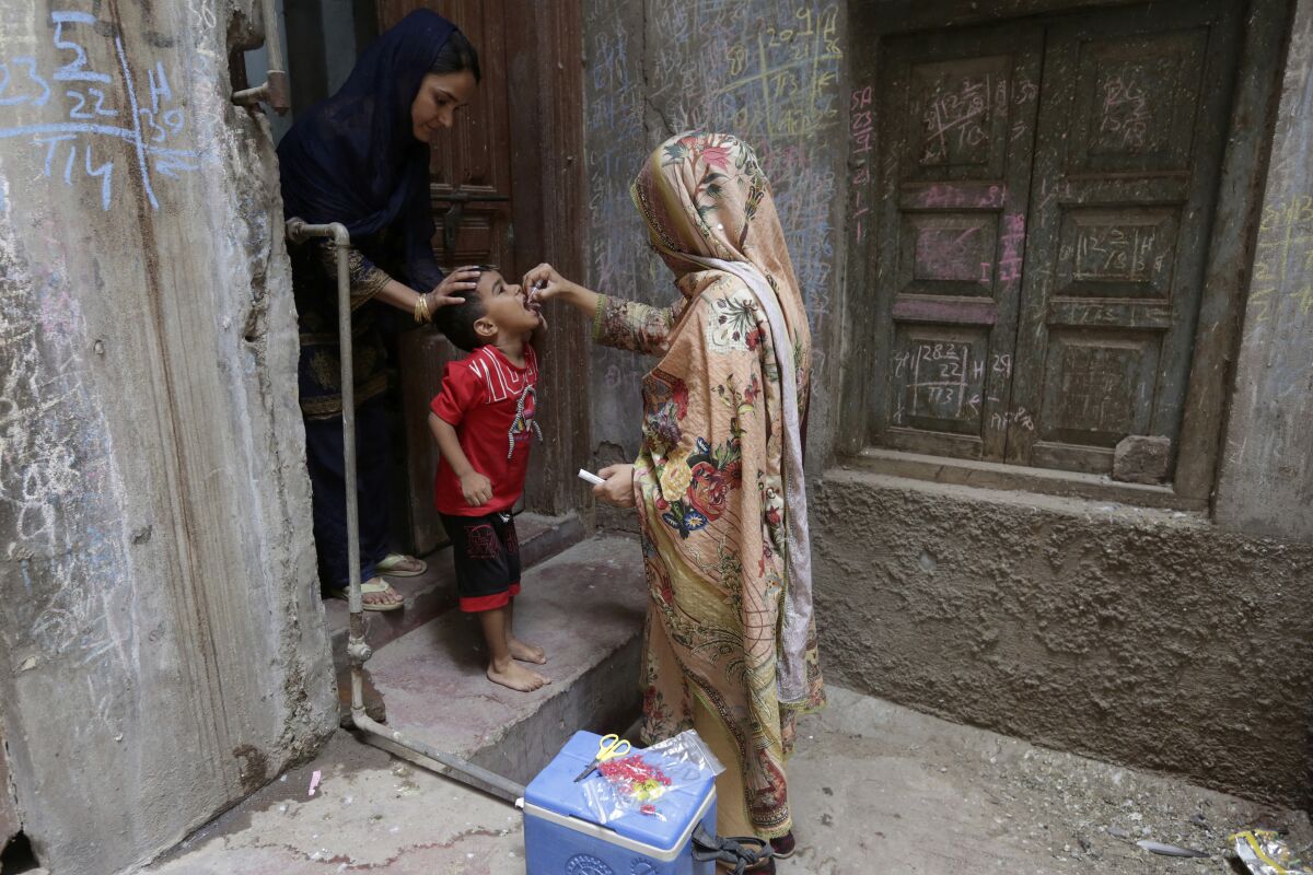 A health worker gives a polio vaccine to a child in a neighborhood of Lahore, Pakistan, Monday, May 23, 2022. Pakistan launched a new anti-polio drive on Monday, more than a week after officials detected the third case so far this year in the country's northwestern region bordering Afghanistan. (AP Photo/K.M. Chaudary)