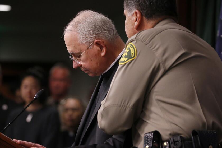 LOS ANGELES, CALIF. - FEB. 20, 2023. Sheriff Robert Luna comforts L.A. Archbishop Jose Gomez during a press conference in downtown Los Angeles on Monday, Feb. 20, 2023, to announce the arrest of a suspect in the murder of Roman Catholic Bishop David O'Connell. Authorities took 65-year-old Carlos Medina into custody early Sunday morning. He is the husband of the housekeeper where O'Connell lived. (Luis Sinco / Los Angeles Times)