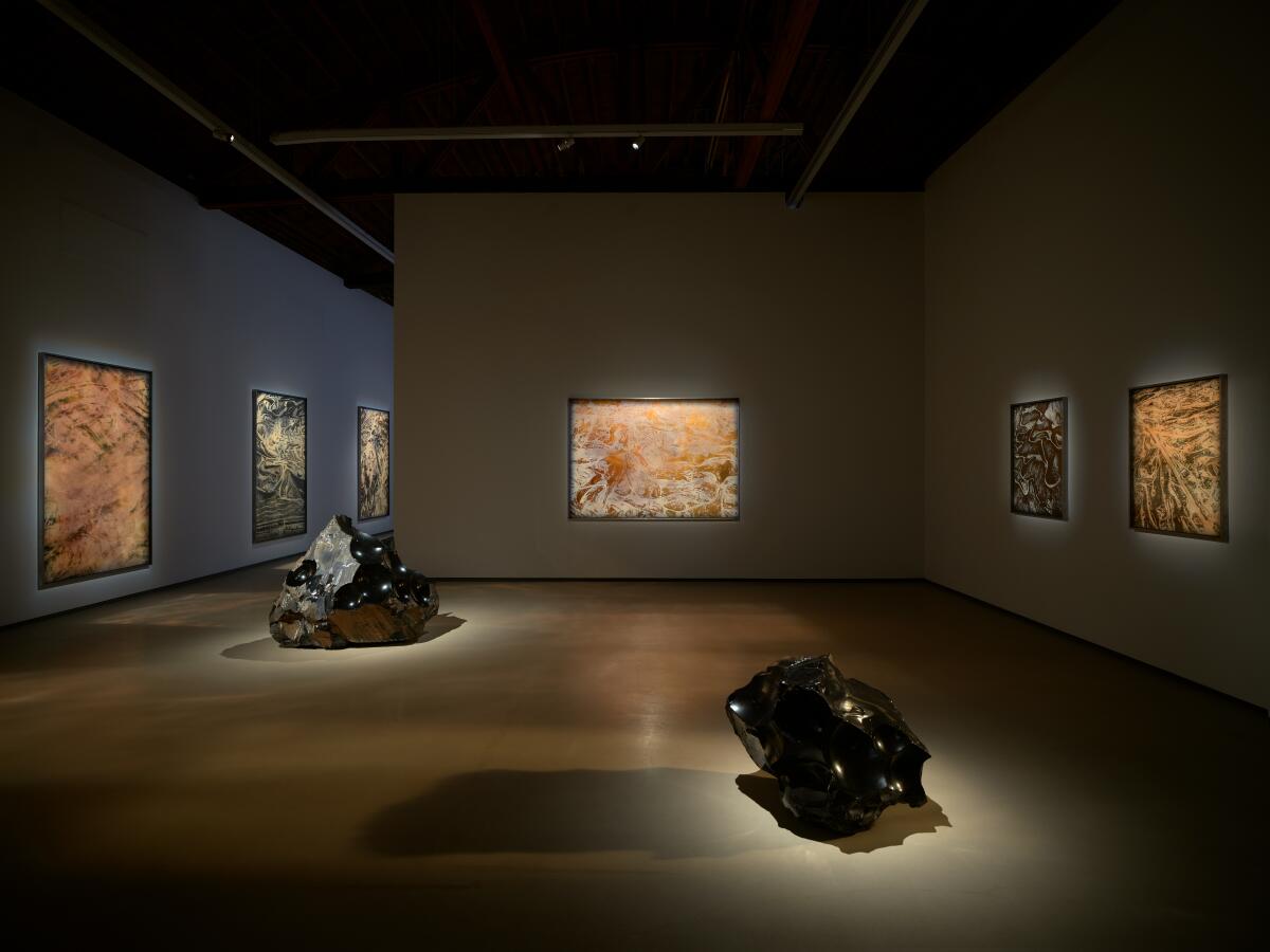Obsidian sculptures and photographs in a dimly lit gallery. 