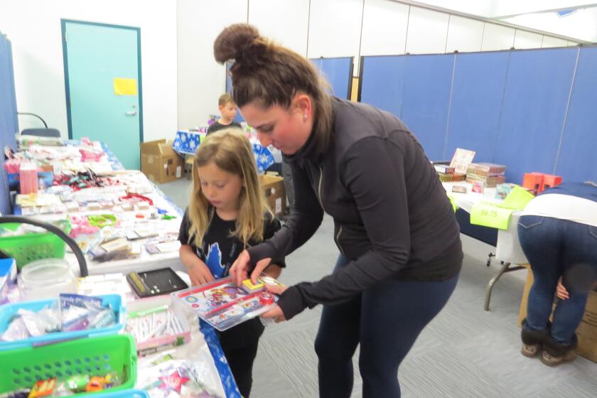 Katelynn Hardee, a kindergartnener at Breeze Hill Elementary in Vista, with her mother Karina. Katelynn raised funds to pay off negative lunch balances for classmates. On Friday, she shopped for gifts at the school holiday boutique.