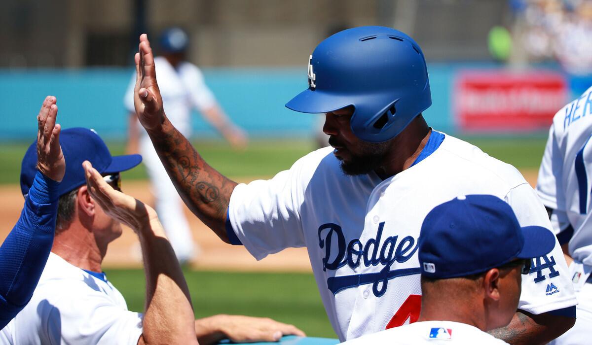 Dodgers' Howie Kendrick, right, celebrates with a high-five as he enters the dugout after scoring on a sacrifice bunt by teammate A.J. Ellis (not in photo) in the second inning against the Arizona Diamondbacks on Tuesday.