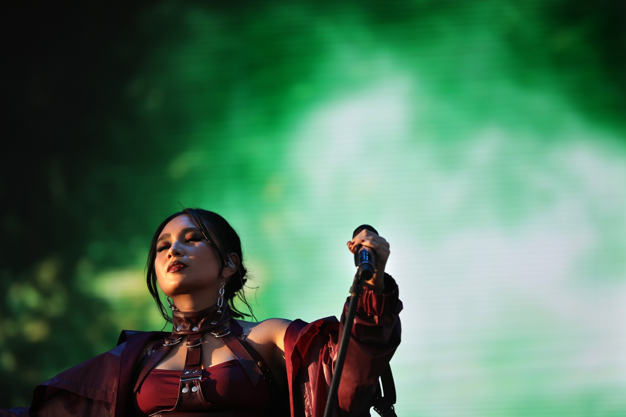 A woman in a red outfit with a leather collar performs.