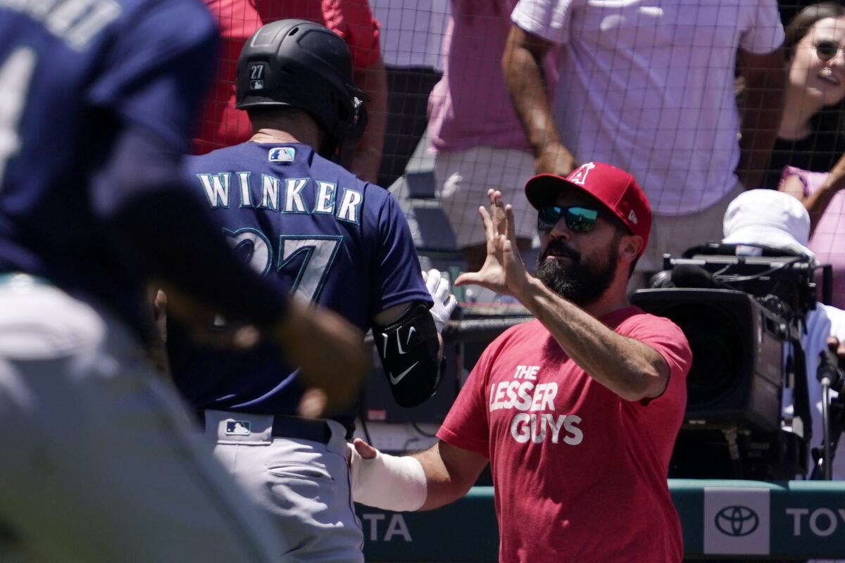 Seattle's Jesse Winker, left, fights with injured Angels third baseman Anthony Rendon during the second inning Sunday.