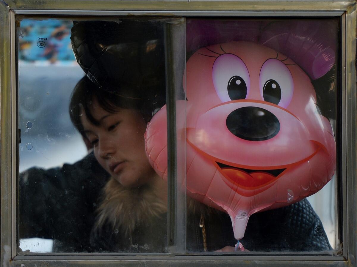 A woman rides a motorcycle taxi with a Disney character Minnie Mouse balloon in Beijing on November 7. Construction has begun on the Shanghai Disney Resort, which will be the first Disney resort in mainland China and is expected to open in late 2015.