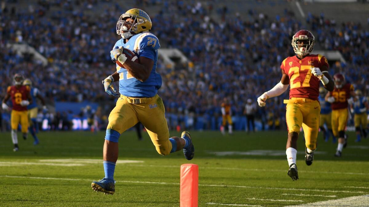 UCLA running Joshua Kelley scores a 55-yard touchdown in front of USC defensive back Ajene Harris in the fourth quarter at the Rose Bowl.