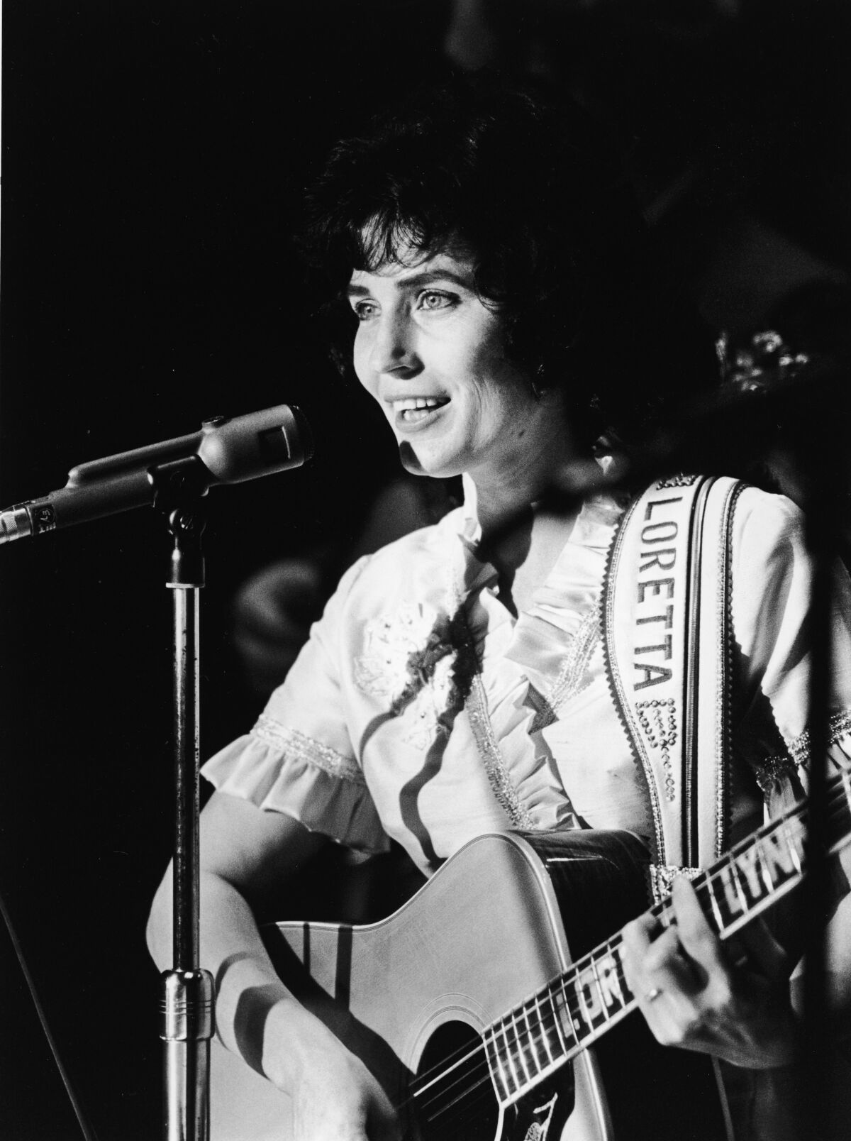 A female country singer performs on stage in the 1960s. 