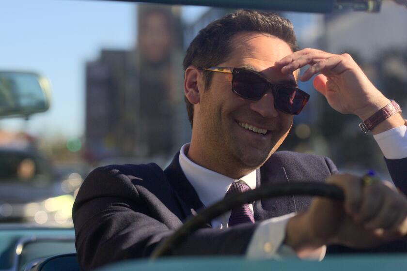 A smiling man in sunglasses driving a convertible