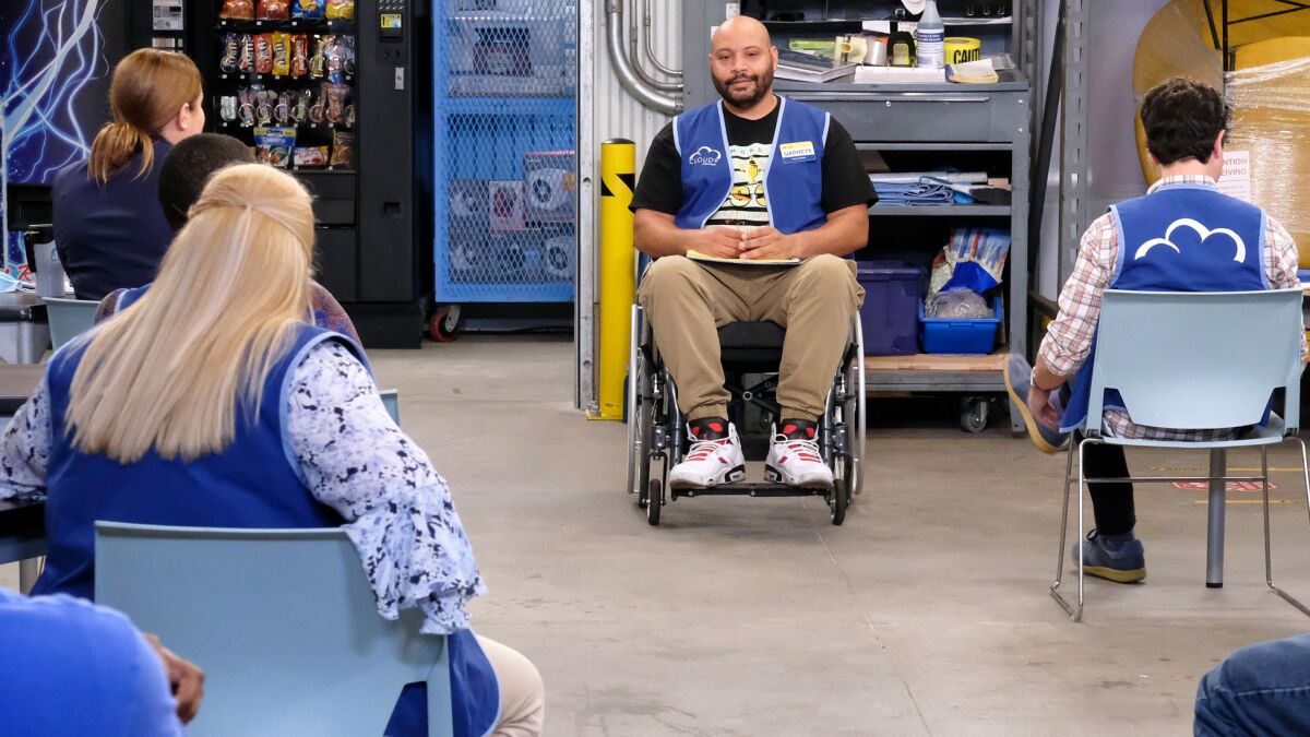 A man in a wheelchair faces people sitting at a room in "Superstore" on NBC.