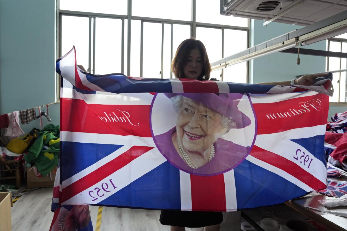 General manager Fan Aiping holds up one of the flag with the Queen's image at the Shaoxing Chuangdong Tour Articles Co. factory in Shaoxing, in eastern China's Zhejiang province, Friday, Sept. 16, 2022. Ninety minutes after Queen Elizabeth II died, orders for thousands of British flags started to flood into the factory south of Shanghai. (AP Photo/Ng Han Guan)