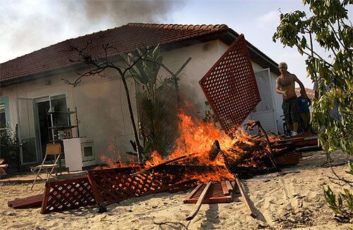 A Neve Dekalim resident sets fire to some of his belongings before leaving. "The settlements must be evacuated; the settlers cannot remain," Israeli Vice Premier Shimon Peres said.