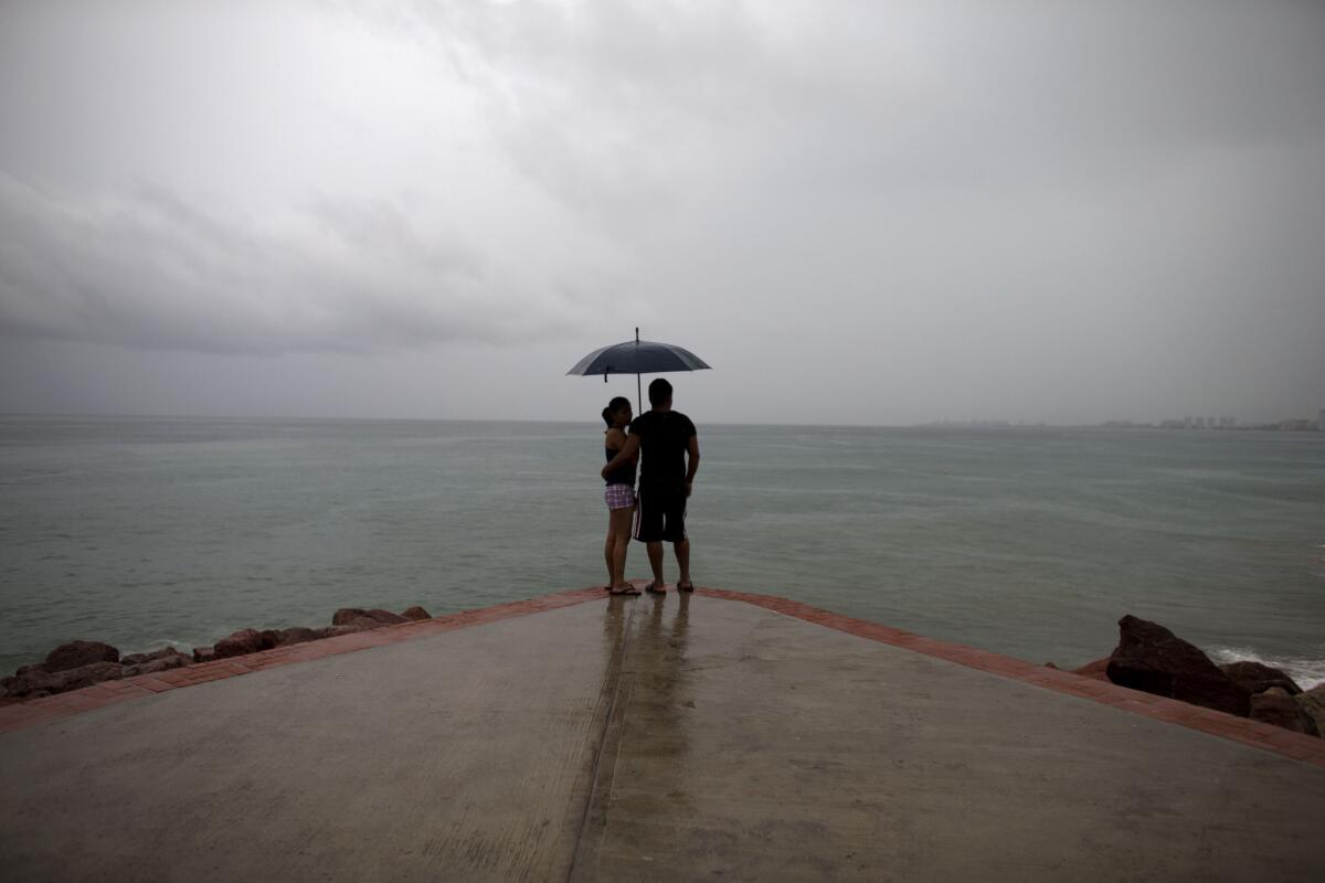 Un pareja mira hacia el mar mientras aumenta la lluvia conforme se acerca el huracán Patricia en Puerto Vallarta, en México, el viernes 23 de octubre de 2015. (AP Foto/Rebecca Blackwell)