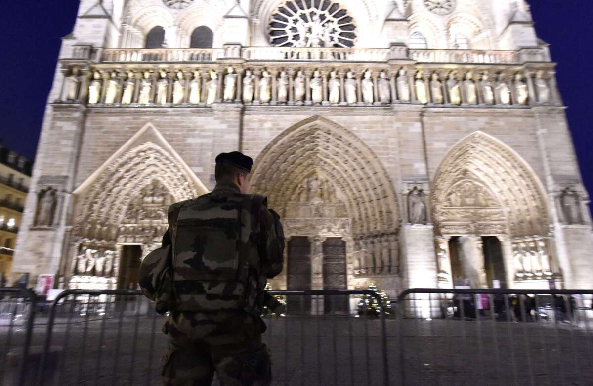A French serviceman stands guard outside the Notre Dame Cathedral as people queue to attend a church service on Dec. 25 in Paris.
