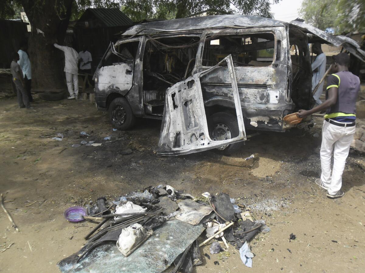 Men inspect a bus following an explosion Feb. 24 on a street in Potiskum, Nigeria.