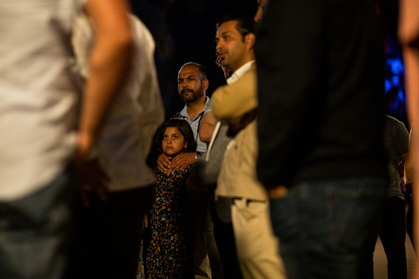 Hanif Ahmadzai embraces his 8-year-old daughter, Zala, as he listens to Shawn VanDiver, founder and president of #AfghanEvac, not pictured, during a gathering at Balboa Park to mark the 1 year anniversary of the U.S. withdrawal from Afghanistan on Tuesday, Aug. 30, 2022. Ahmadzai evacuated Afghanistan on Aug. 23, 2021, and traveled through Qatar and Germany before arriving at Washington D.C. on Sept. 8. He then moved to an Army camp at Indiana and finally settled in San Diego in December.