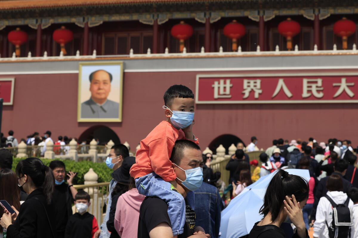 A man and child wearing masks visit Tiananmen Gate near the portrait of Mao Zedong in Beijing on May 3, 2021. China’s population growth is falling closer to zero as fewer couples have children, the government announced Tuesday, May 11, 2021, adding to strains on an aging society with a shrinking workforce. (AP Photo/Ng Han Guan)