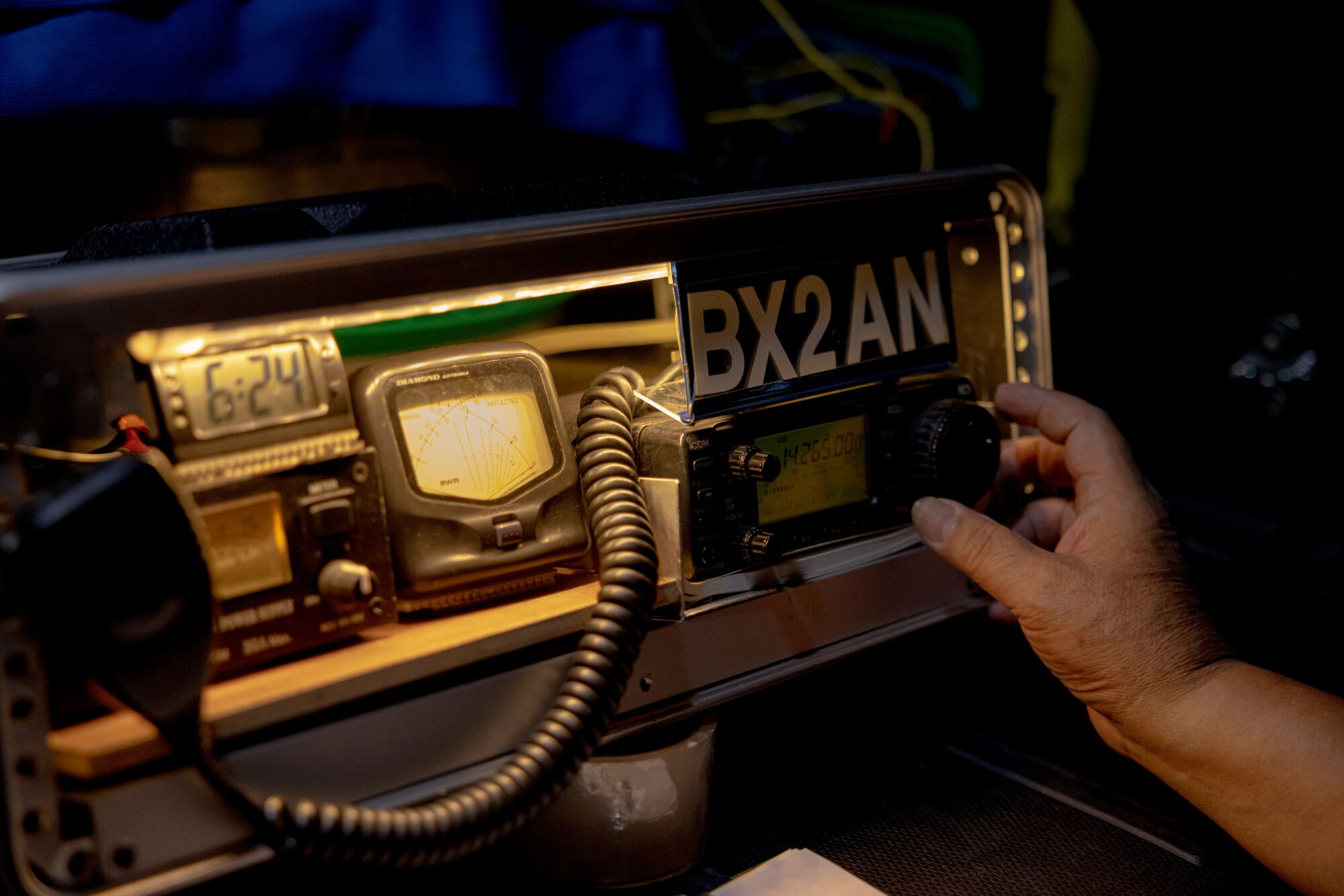 A hand adjusts the knob on a machine with various screens and a sign that reads "BX2AN"