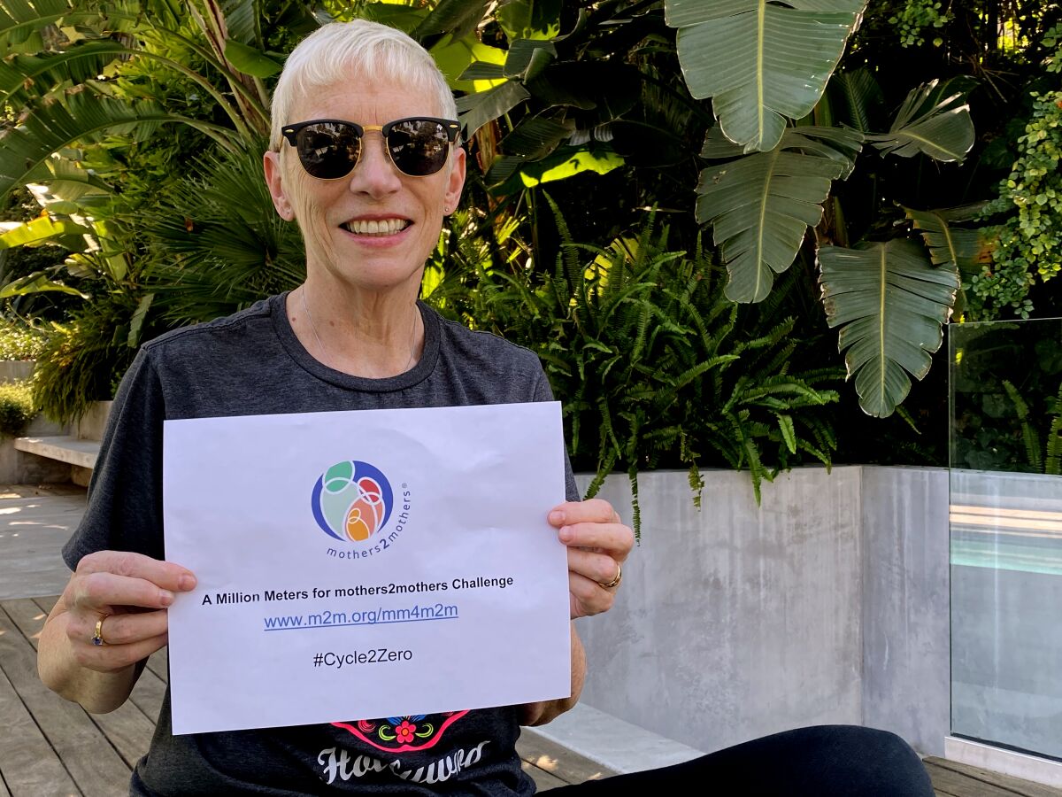 Singer Annie Lennox holds a piece of paper with the Mothers2mothers logo