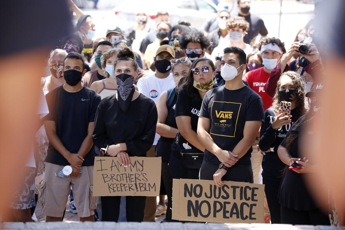 People stand and listen during the Juneteenth event, sponsored by Black O.C., at Sasscer Park in Santa Ana on Friday.