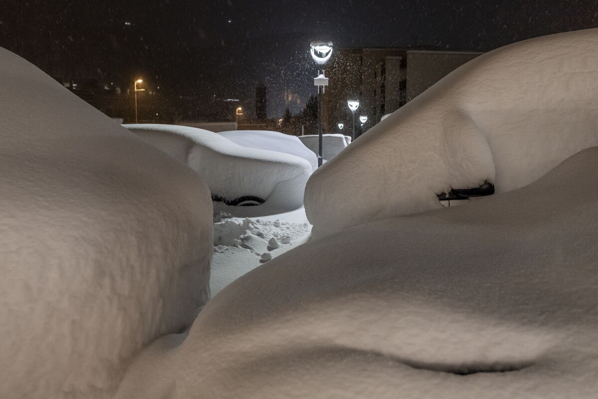 Cars are covered with snow in St. Moritz, Switzerland, Saturday, Dec. 5, 2020. Due to a heavy snowfall and strong wind, the FIS decided to cancel women's Super-G race of the FIS Alpine Ski World Cup on Saturday. (Jean-Christophe Bott/Keystone via AP)