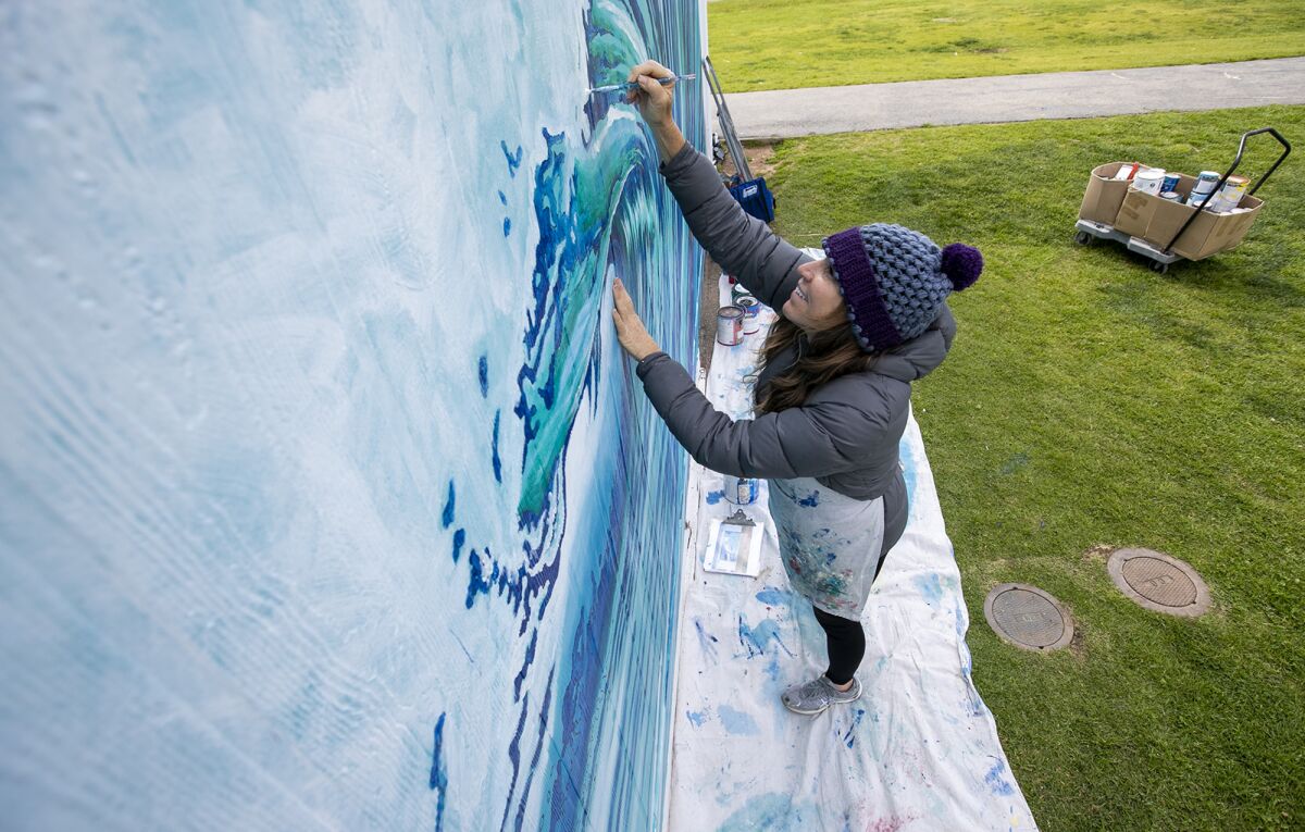 Costa Mesa resident Jennifer Bloomfield works on one of seven murals that she was commissioned to paint on campus.