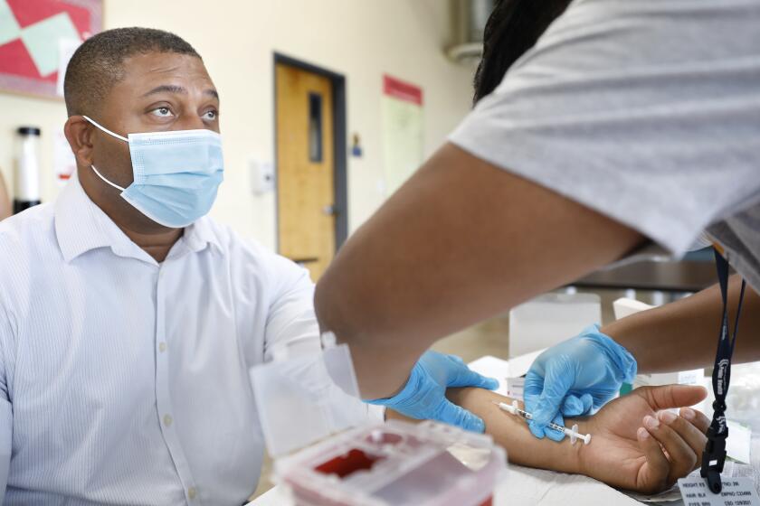 LOS ANGELES, CA - AUGUST 23, 2022: Steven Mitchell, Project Director with The People Concern, receives the monkeypox vaccine by Jeremy Oyague, right, a registered nurse with The Los Angeles Department of Public Health at a vaccination clinic to immunize people against monkeypox and COVID at The Village Mental Health Services in Los Angeles, a site run by The People Concern. (Christina House / Los Angeles Times)