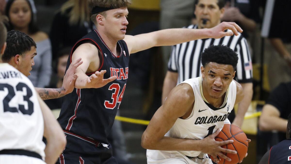 Colorado guard Tyler Bey, right, collects a loose ball as Utah center Jayce Johnson defends during the first half on Saturday.